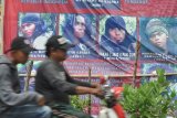 Seorang pengendara sepeda motor melintas di depan baliho DPO (Daftar Pencarian Orang) tindak pidana terorisme yang dipasang dipinggir jalan umum di Kabupaten Donggala, Sulawesi Tengah, Kamis (19/4). Polri kembali memperpanjang masa Operasi Tinombala guna mencari sisa DPO kasus terorisme diwilayah Sulawesi Tengah yang kini tersisa 7 orang. Selain dihimbau untuk menyerahkan diri, polisi juga meminta masyarakat untuk melaporkan bila melihat keberadaan tersangka teroris dalam DPO tersebut.  (ANTARA FOTO/Mohamad Hamzah)