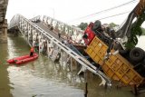 Petugas mengevakuasi truk di lokasi jembatan Widang yang runtuh, Tuban, Jawa Timur, Selasa (17/4). Sisi barat jembatan itu runtuh sekitar 50 meter dan mengakibatkan satu pengemudi truk meninggal dunia, dan melukai tiga korban lainnya, sementara tiga truk dan sebuah sepeda motor masuk ke Bengawan Solo. ANTARA FOTO/Aguk Sudarmojo/foc/17.