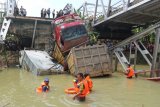 Petugas mengevakuasi truk di lokasi jembatan Widang yang runtuh, Tuban, Jawa Timur, Selasa (17/4). Sisi barat jembatan itu runtuh sekitar 50 meter dan mengakibatkan satu pengemudi truk meninggal dunia, dan melukai tiga korban lainnya, sementara tiga truk dan sebuah sepeda motor masuk ke Bengawan Solo.  (ANTARA FOTO/Aguk Sudarmojo)