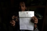 Parsin anak kedua dari Parinah, TKW Indonesia yang telah hilang selama 18 tahun, menunjukan foto ibunya beserta surat terakhir ibunya yang meminta bantuan untuk dipulangkan dari Inggris, di rumahnya di Desa Petarangan, Kemranjen, Banyumas, Senin (9/4). KBRI London, Inggris, menyelamatkan Parinah, TKW asal Banyumas, Jateng, yang telah hilang kontak selama 18 tahun, dan menjadi korban tindakan perbudakan modern yang dilakukan oleh empat orang majikanya.  (ANTARA FOTO/Idhad Zakaria)