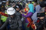 Personel Polisi Wanita (Polwan) Polres Metro Jakarta Timur yang mengenakan busana kebaya, membantu mengenakan helm kepada penggendara sepeda motor ketika mengatur arus lalu lintas di Jalan Otista Raya, Jatinegara, Jakarta, Jumat (20/4). Kegiatan tersebut dalam rangka memperingati Hari Kartini. ANTARA FOTO/Aprillio Akbar/Spt/18.