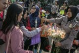 Petugas kepolisian membagikan bunga kepada warga sebagai bentuk simpati belasungkawa pada kegiatan solidaritas untuk Kepolisian Republik Indonesia di Car Free Day Dago, Bandung, Jawa Barat, Minggu (13/5). Aksi yang digagas Kepolisian Daerah Jawa Barat tersebut guna mengajak partisipasi, empati dan simpati masyarakat atas meninggalnya enam anggota kepolisian pada peristiwa kerusuhan Mako Brimob serta bersikap dan mendukung gerakan untuk tidak takut terhadap aksi terorisme. ANTARA JABAR/Novrian Arbi/agr/18