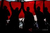 Siluet buruh membawa bendera merah putih saat aksi Hari Buruh Internasional di depan Gedung Sate, Bandung, Jawa Barat, Selasa (1/5). Dalam aksinya mereka meminta kepada Pemerintah untuk meningkatkan kesejahteraan para kaum buruh. ANTARA JABAR/M Agung Rajasa/agr/18
