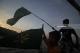 Dua anak kampung nelayan Nambangan dan Bulak Cumpat, Surabaya membentangkan bendera saat mengikuti pembacaan salawat 