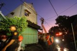 Teknisi PLN memotong kabel listrik yang melintang pada rumah yang terbakar di Jalan Kebalen Kulon 2 no 9, Surabaya, Jawa Timur, Selasa (29/5/2018). Kebakaran rumah indekos tersebut menelan 8 korban meninggal. (ANTARA FOTO/Didik Suhartono)