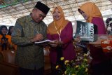 Menteri Pendidikan dan Kebudayaan (Mendikbud) Muhadjir Effendy (kiri) melayani permintaan tanda tangan pada buku yang disodorkan guru usai menjadi pembicara dalam seminar akbar nasional di Gelanggang Olah Raga (GOR) Ki Mageti, Magetan, Jawa Timur, Jumat (11/5). Ribuan guru mengikuti seminar dengan pembicara utama Muhadjir Effendy dengan tema Meningkatkan Mutu Pendidikan yang Berkarakter dan Berprestasi. Antara Jatim/Foto/Siswowidodo/mas/18