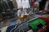 Pedagang membaca Alquran sembari menunggu pembeli saat berjualan di pertokoan kawasan Masjid Ampel, Surabaya, Jawa Timur, Selasa (22/5). Dalam bulan Ramadan umat muslim memperbanyak amal ibadah seperti membaca Al Quran di setiap kesempatan. Antara Jatim/Moch Asim/zk/18