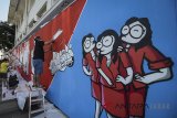 Seniman mural jalanan dari The Popop menggambar mural dengan tema 