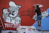 Seniman mural jalanan dari The Popop menggambar mural dengan tema 