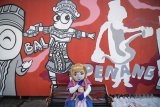 Seniman mural jalanan dari The Popop menggambar mural dengan tema 