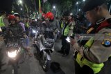 Polisi memeriksa surat kelengkapan kendaraan milik pengguna motor yang terjaring razia cipta kondisi di Jalan Darmo, Surabaya, Jawa Timur, Sabtu (26/5) malam. Operasi yang digelar Polrestabes Surabaya itu memeriksa kelengkapan surat kendaraan bermotor dan barang bawaannya guna mengantisipasi peredaran minuman keras, narkoba, senjata tajam atau bahan-bahan berbahaya serta untuk memberikan rasa aman kepada masyarakat. ANTARA FOTO/Didik Suhartono/18