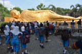 Pengunjung mengamati patung Buddha tidur di Maha Vihara Mojopahit, Trowulan, Mojokerto, Jawa Timur, Rabu (9/5). Patung yang memiliki panjang 22 meter, lebar 6 meter,serta tinggi 4,5 meter dan diklaim sebagai patung Buddha Tidur terbesar ketiga di Asia setelah Thailand dan Nepal tersebut menjadi salah satu tempat wisata favorit yang banyak dikunjungi wisatawan. Antara Jatim/Umarul Faruq/zk/18