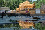 Pengunjung mengamati patung Buddha tidur di Maha Vihara Mojopahit, Trowulan, Mojokerto, Jawa Timur, Rabu (9/5). Patung yang memiliki panjang 22 meter, lebar 6 meter,serta tinggi 4,5 meter dan diklaim sebagai patung Buddha Tidur terbesar ketiga di Asia setelah Thailand dan Nepal tersebut menjadi salah satu tempat wisata favorit yang banyak dikunjungi wisatawan. Antara Jatim/Umarul Faruq/zk/18