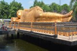 Pengunjung mengamati patung Buddha tidur di Maha Vihara Mojopahit, Trowulan, Mojokerto, Jawa Timur, Rabu (9/5). Patung yang memiliki panjang 22 meter, lebar 6 meter,serta tinggi 4,5 meter dan diklaim sebagai patung Buddha Tidur terbesar ketiga di Asia setelah Thailand dan Nepal tersebut menjadi salah satu tempat wisata favorit yang banyak dikunjungi wisatawan. Antara Jatim/Umarul Faruq/zk/18