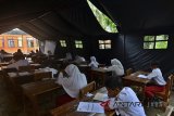 Siswa mengikuti Ujian Sekolah Berstandar Nasional (USBN) di dalam tenda darurat di Madrasah Ibtidaiyah (MI) Pasawahan, Dusun Ciakar, Kabupaten Ciamis, Jawa Barat, Rabu (3/5). Para siswa terpaksa melaksanakan USBN di dalam tenda darurat meskipun dalam kondisi panas dan berdebu, karena tiga ruang kelas roboh serta tiga kelas tidak bisa digunakan akibat pergerakan tanah terus terjadi. ANTARA FOTO/Adeng Bustomi/agr/18