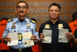 Kepala Kantor Imigrasi Klas 1 Khusus Bandara Soetta Enang Syamsi (kiri) didampingi Kepala Bidang Pengawasan dan Tindakan Barron Ichsan (kanan) menunjukan paspor palsu seusai memberikan keterangan pers terkait pengungkapan kasus pemalsuan paspor oleh empat orang Warga Negara Asing (WNA) di Kawasan Bandara Soekarno Hatta, Tangerang, Banten, Kamis (24/5/2018). Kantor Imigrasi Bandara Soetta berhasil mengungkap pemalsuan paspor Indonesia yang akan digunakan keluar menuju Yunani yang digunakan oleh WNA Bangladesh, Solomon, Nigeria dan Pakistan. Selain mengamankan empat orang pemalsu paspor imigrasi, pihak bandara juga mengamankan enam orang WNA yang overstay di Indonesia. (ANTARA /Muhammad Iqbal) 