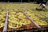 Pekerja mengangkat krupuk mie kuning yang selesai dijemur di sentra pembuatan kerupuk kuning di Karadenan, Bogor, Jawa Barat, Selasa (22/5). Pengusaha kerupuk mie kuning mengeluhkan kenaikan bahan baku di Bulan Ramadan, hal ini disebabkan karena harga bahan baku krupuk yaitu sagu mengalami kenaikan hingga 30 persen. ANTARA JABAR/Yulius Satria Wijaya/agr/18.
