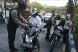 Petugas kepolisian memeriksa pengendara kendaraan bermotor di pintu masuk Mapolda Bali, Denpasar, Senin (14/5/2018). Petugas memperketat penjagaan kawasan Markas Polda Bali pascaledakan bom di sejumlah titik di Surabaya. (ANTARA /Fikri Yusuf) 