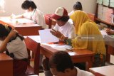 Seorang guru pedamping membacakan soal Ujian Sekolah Berstandar Nasional (USBN) kepada murid berkebutuhan khusus di SD Inklusi Betet I, Kota Kediri, Jawa Timur, Kamis (3/5). USBN yang wajib diikuti oleh siswa reguler dan juga siswa berkebutuhan khusus tersebut sebagai syarat tamat belajar. Antara Jatim/Prasetia Fauzani/mas/18.