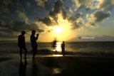 Wisatawan menikmati suasana pagi dengan melihat matahari terbit di Pantai Boom, Banyuwangi, Jawa Timur, Jumat (11/5). Kabupaten Banyuwangi yang memiliki julukan Sunrise of Java tersebut, menjadi tujuan wisatawan untuk menikmati suasana matahari terbit pertama di pulau Jawa. Antara Jatim/Budi Candra Setya/mas/18.