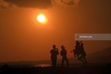 Wisatawan menikmati suasana pagi dengan melihat matahari terbit di Pantai Boom, Banyuwangi, Jawa Timur, Jumat (11/5). Kabupaten Banyuwangi yang memiliki julukan Sunrise of Java tersebut, menjadi tujuan wisatawan untuk menikmati suasana matahari terbit pertama di pulau Jawa. Antara Jatim/Budi Candra Setya/mas/18.