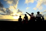 Wisatawan menikmati suasana pagi dengan melihat matahari terbit di Pantai Boom, Banyuwangi, Jawa Timur, Jumat (11/5). Kabupaten Banyuwangi yang memiliki julukan Sunrise of Java tersebut, menjadi tujuan wisatawan untuk menikmati suasana matahari terbit pertama di pulau Jawa. Antara Jatim/Budi Candra Setya/mas/18.