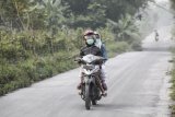 Warga melintasi jalan yang diselimuti abu vulkanik letusan Gunung Merapi di Muntilan, Jawa Tengah, Kamis (24/5). Sejumlah daerah di kawasan Magelang, Jawa Tengah terkena hujan abu vulkanik akibat letusan Gunung Merapi yang terjadi pada Kamis (24/5) pukul 02.56 WIB dengan durasi 4 menit dan tinggi kolom (asap letusan) 6.000 meter. ANTARA FOTO/Andreas Fitri Atmoko/foc/18.