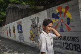 Warga berjalan di samping mural bertema Asian Games di kawasan Jati Padang Utara, Pasar Minggu, Jakarta, Selasa (8/5). Mural tersebut dibuat untuk sosialisasi dan mendukung perhelatan Asian Games pada Agustus 2018. ANTARA FOTO/Aprillio Akbar/foc/18.