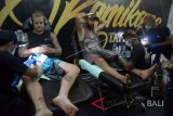 Sejumlah seniman tato menggambar tubuh wisatawan saat Bali Tattoo Expo 2018 di Gedung Bali Creative Industry Center (BCIC) Denpasar, Jumat (18/5). Kegiatan yang berlangsung selama tiga hari tersebut diikuti 132 studio tato dari berbagai negara seperti Australia, Malaysia, Singapura, Austria, Filipina, India, Mesir, dan Slovenia dengan harapan dapat mengembangkan industri seni tato khususnya di kawasan Bali. ANTARA FOTO/Wira Suryantala/wdy/2018.