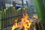 Warga memasak lemang bambu menggunakan bahan bakar kayu di desa Lambaro Skeep, Banda Aceh, Kamis (17/5). Lemang bambu merupakan makanan tradisional yang ramai dijual pedagang pada bulan ramadan sebagai menu berbuka puasa yang dijual seharga Rp30.000 hingga Rp100.000 per batang sesuai ukuran. (ANTARA FOTO/Ampelsa/aww/18)