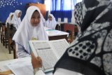 Seorang murid SMP mengikuti uji baca Alquran saat mengikuti tes masuk SMA Negeri 4, di Banda Aceh, Selasa (22/5). Provinsi Aceh sebagai daerah Syariat Islam, menerapkan uji baca Alquran sebagai salah satu persyaratan masuk sekolah mulai SD, SMP dan SMA pada setiap tahun ajaran baru menurut tingkat pendidikannya. (ANTARA FOTO/Ampelsa/ama/18)