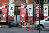 Warga melintas di depan poster pasangan calon Gubenur dan Wakil Gubernur Bali di Jalan Hayam Wuruk, Denpasar, Bali, Minggu (20/5). KPU Provinsi Bali menetapkan daftar pemilih tetap (DPT) pada Pilkada 2018 mencapai 2.982.201 pemilih yang tersebar pada 6.296 tempat pemungutan suara di sembilan kabupaten/kota di Provinsi Bali. ANTARA FOTO/Wira Suryantala/wdy/2018.