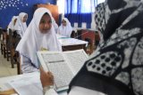 Seorang murid SMP mengikuti uji baca Alquran saat mengikuti tes masuk SMA Negeri 4, di Banda Aceh, Selasa (22/5). Provinsi Aceh sebagai daerah Syariat Islam, menerapkan uji baca Alquran sebagai salah satu persyaratan masuk sekolah mulai SD, SMP dan SMA pada setiap tahun ajaran baru menurut tingkat pendidikannya. ANTARA FOTO/Ampelsa/ama/18