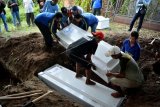 Warga memasukkan peti jenazah terduga teroris ke dalam liang lahat di pemakaman kawasan Pucang, Sidoarjo, Jawa Timur, Jumat (18/5). Sebanyak tiga jenazah terduga teroris pada ledakan bom di rusunawa Wonocolo Sidoarjo tersebut terdiri dari Anton Ferdiantono, Sari Puspitarini dan anaknya Hilya Auliya R. ANTARA FOTO/Umarul Faruq/aww/18.