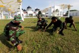 Prajurit Kodam Iskandar Muda membersihkan sampah dan rumput di halaman masjid raya Baiturrahman, Banda Aceh, Aceh, Jumat (11/5). Pembersihan rumah ibadah, fasilitas umum dan tempat wisata yang melibatkan prajurit TNI, Polri dan Aparatur Sipil Negara (ASN) di jajaran Pemerintahan Kota Banda Aceh dilaksanakan dalam rangka menyambut bulan Ramadhan. (ANTARA FOTO/Irwansyah Putra/18)