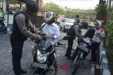 Petugas kepolisian memeriksa pengendara kendaraan bermotor di pintu masuk Mapolda Bali, Denpasar, Senin (14/5). Petugas memperketat penjagaan kawasan Markas Polda Bali pascaledakan bom di sejumlah titik di Surabaya. ANTARA FOTO/Fikri Yusuf/wdy/2018.