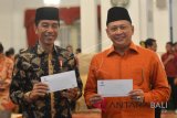 Presiden Joko Widodo (kiri) bersama Ketua DPR Bambang Soesetyo memperlihatkan tanda terima pembayaran zakat seusai membayar zakat di Istana Negara, Jakarta, Senin (28/5). Presiden bersama sekitar 300 pejabat kementerian / lembaga tinggi negara dan direksi BUMN melakukan pembayaran zakat melalui Baznas . ANTARA FOTO/Wahyu Putro A/wdy/2018