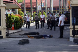 Petugas kepolisian mengevakuasi dua jenazah pelaku penyerangan di jalan pintu masuk Polda Riau di Pekanbaru, Riau, Jumat (16/5). Sejumlah pria menggunakan mobil minibus mencoba menerobos dan melakukan penyerangan ke Polda Riau pada sekitar pukul 09.00 Wib.  (ANTARA FOTO/Retmon)