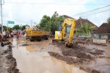 Sebuah alat berat membersihkan lumpur akibat banjir bandang yang melanda Banyuwangi, Jawa Timur, Jumat (22/6). Akibat banjir bandang tersebut puluhan rumah rusak dan sejumlah  ruas jalan sulit dilalui serta lahan pertanian milik warga rusak. Antara jatim/Tulus Harjono/zk/18