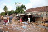Warga membersihkan lumpur akibat banjir bandang yang melanda Banyuwangi, Jawa Timur, Jumat (22/6). Akibat banjir bandang tersebut puluhan rumah rusak dan sejumlah  ruas jalan sulit dilalui serta lahan pertanian milik warga rusak. Antara jatim/Tulus Harjono/zk/18
