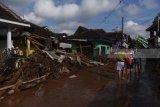 Warga dan relawan  membersihkan rumahnya dari material pasir dan lumpur akibat banjir bandang di Desa Alas Malang, Singojuruh, Banyuwangi, Jawa Timur, Sabtu (23/6). Akibat kejadian tersebut sedikitnya 328 unit rumah rusak  dan meninggalkan endapan lumpur dan pasir setinggi satu meter di pemukiman warga. Antara Jatim/Zabur Karuru/18