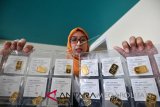 Karyawan saat menunjukkan contoh emas batangan yang dijual di Butik Emas Logam Mulia, gedung Sarinah, Jakarta, Senin (28/5/18). Berdasarkan harga acuan kantor Antam Pulo Gadung, harga jual emas Antam pada perdagangan Senin (28/5) turun Rp4.000 menjadi Rp656 ribu per gram, sementara harga 