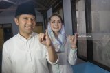 Cawagub Jatim Emil Elestianto Dardak (kiri) didampingi istri, Arumi Bachsin (kanan) menunjukkan bekas tinta diujung jari kelingking mereka tanda telah menyalurkan hak pilih (mencoblos) di TPS 05 Kelurahan Ngantru, Trenggalek, Jawa Timur, Rabu (27/6). Emil yang maju bursa Pilkada Jatim mendampingi Cagub Khofifah Indar Parawansa mengawali rangkaian penggunaan hak pilihnya dengan sungkem ke orang tua dan ziarah makam leluhur sebelum mencoblos di TPS 05 Kelurahan Ngantru, Trenggalek. Antara Jatim/Destyan Sujarwoko/zk/18