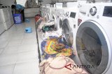 Pekerja menyuci pakaian ke dalam mesin cuci di Bogor Laundry, Bogor, Jawa Barat, Senin (25/6). Jasa laundry pakaian yang memanfaatkan energi gas Perusahaan Gas Negara (PGN) untuk kegiatan operasional tersebut mengalami peningkatan permintaan jasa mencuci pakaian sebesar 40 persen pasca libur Lebaran dengan tarif mulai Rp.13 ribu hingga Rp.30 ribu tergantung berat dan jenis barang yang dicuci. ANTARA FOTO/Arif Firmansyah/18