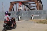 Warga melintas di depan jembatan lama Kertosono yang ditutup total di Kertosono, Nganjuk, Jawa Timur, Senin (11/6). Memasuki musim mudik lebaran jembatan peninggalan Belanda penghubung Kabupaten Nganjuk dengan Kabupaten Kediri itu ditutup total oleh polisi karena hampir roboh. Antara Jatim/Prasetia Fauzani/zk/18