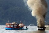 Sejumlah warga berusaha memadamkan api melalap kapal penangkap ikan KM Sari Segara 29 di perairan Desa Laha, Teluk Ambon, Maluku, Senin (4/6/2018). Kapal tersebut terbakar akibat dibakar oleh Anak Buah Kapal (ABK) kapal penangkap ikan KM Matahari Abadi yang terlibat perkelahian dengan ABK KM Sari Segara 29. (ANTARAFOTO/izaac mulyawan)