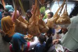 Warga mengantre untuk mendapatkan hidangan ketupat gratis di Kampung Sukolilo, Kenjeran, Surabaya, Jawa Timur, Jumat (22/6). Tradisi Lebaran Ketupat yang dirayakan pada hari ketujuh setelah Hari Raya Idul Fitri bagi warga di kampung tersebut dimeriahkan dengan membagikan hidangan ketupat secara gratis kepada warga lainnya. Antara Jatim/Moch Asim/18