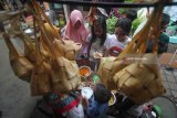 Warga mengantre untuk mendapatkan hidangan ketupat gratis di Kampung Sukolilo, Kenjeran, Surabaya, Jawa Timur, Jumat (22/6). Tradisi Lebaran Ketupat yang dirayakan pada hari ketujuh setelah Hari Raya Idul Fitri bagi warga di kampung tersebut dimeriahkan dengan membagikan hidangan ketupat secara gratis kepada warga lainnya. Antara Jatim/Moch Asim/18