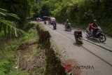 Pemudik melintas disamping jalan yang longsor di jalur altenatif Sumedang-Subang, Rancakalong, Kabupaten Sumedang, Jawa Barat, Selasa (12/6). Longsor akibat intensitas hujan yang tinggi pada beberapa bulan lalu tersebut hingga H-3 Hari Raya Idulfitri 1439 H belum diperbaiki. ANTARA JABAR/Raisan Al Farisi/agr/18