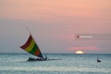 Pengunjung bermain perahu layar di Pantai Pasir Putih Situbondo, Jawa Timur, Minggu (17/6). Masyarakat memanfaatkan libur Lebaran dengan menikmati matahari terbenam, berenang di laut, naik perahu layar dan bermain kano. Antara Jatim/Seno/zk/18.